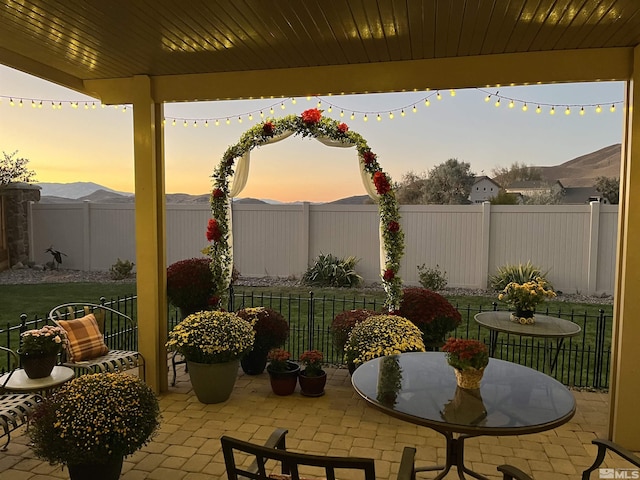 patio terrace at dusk featuring a mountain view and a lawn