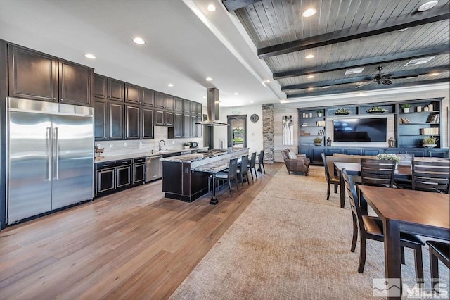 kitchen featuring a kitchen bar, light wood-type flooring, a kitchen island, island range hood, and appliances with stainless steel finishes