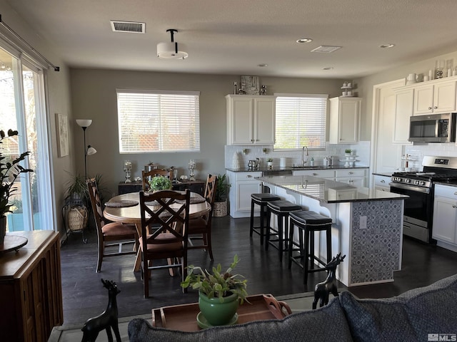 kitchen featuring appliances with stainless steel finishes, white cabinetry, a center island, and sink