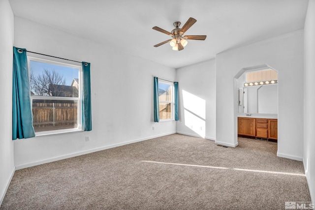 unfurnished bedroom featuring ceiling fan, light colored carpet, and connected bathroom