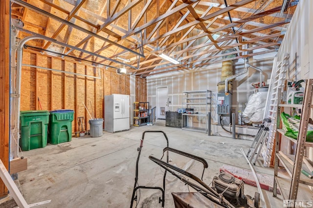 garage with a garage door opener, white fridge with ice dispenser, and heating unit