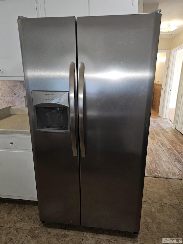 room details featuring stainless steel refrigerator with ice dispenser and white cabinets