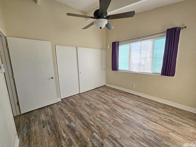 unfurnished bedroom with hardwood / wood-style floors, a closet, ceiling fan, and vaulted ceiling