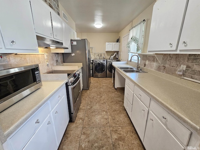 kitchen with sink, stainless steel appliances, washer and dryer, and white cabinetry