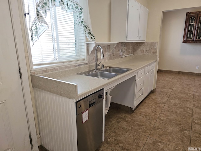 kitchen with sink, white cabinetry, dark tile patterned flooring, stainless steel dishwasher, and decorative backsplash