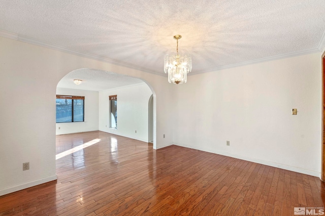 spare room with ornamental molding, a textured ceiling, a chandelier, and hardwood / wood-style flooring