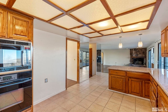 kitchen with plenty of natural light, light stone countertops, black appliances, and a stone fireplace