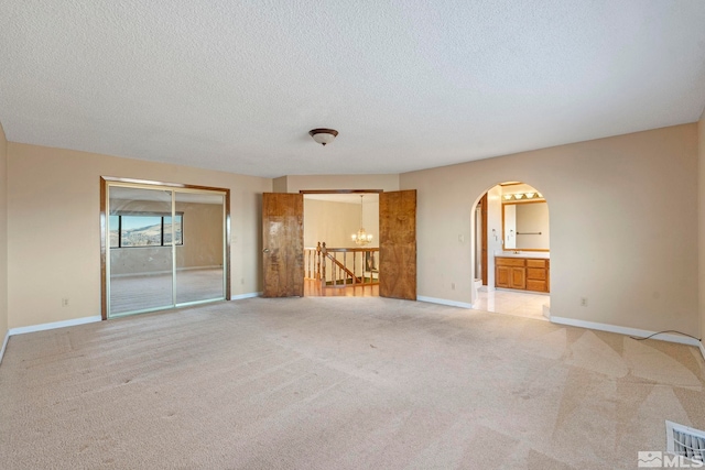 empty room featuring a textured ceiling and light colored carpet