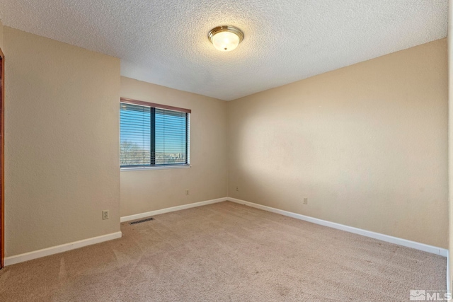 empty room with a textured ceiling and light colored carpet