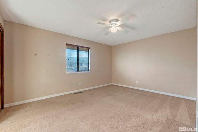 spare room featuring a textured ceiling, carpet floors, and ceiling fan