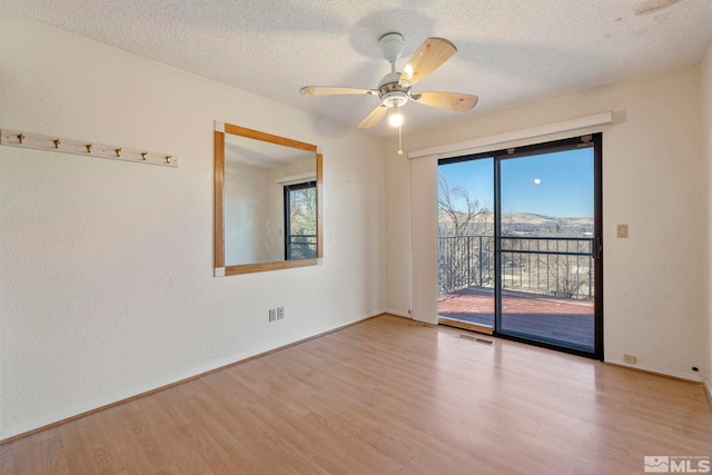 empty room with ceiling fan, light hardwood / wood-style flooring, and a textured ceiling