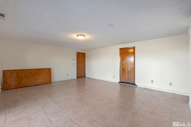 tiled spare room featuring a textured ceiling