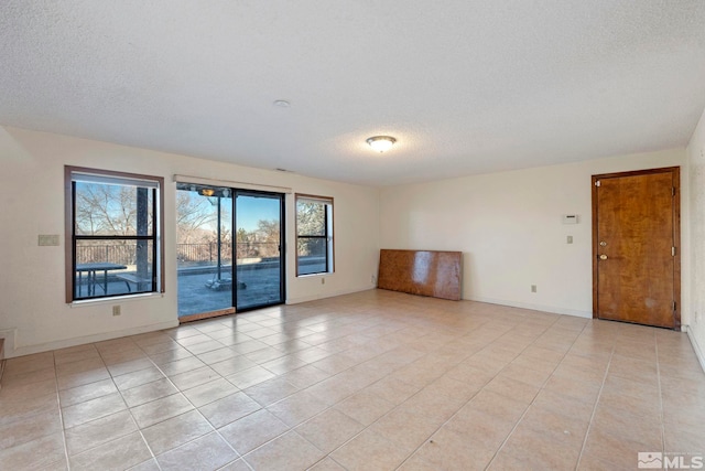 tiled empty room featuring a textured ceiling