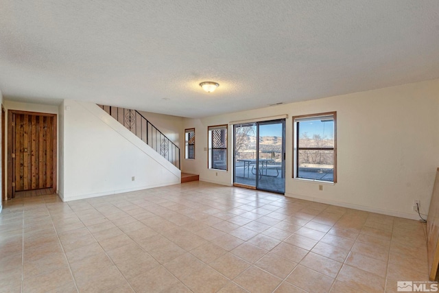 spare room featuring light tile patterned flooring and a textured ceiling