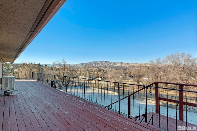 deck with central air condition unit, a covered pool, and a mountain view