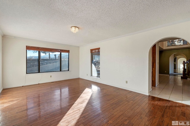 empty room featuring a textured ceiling, hardwood / wood-style floors, and crown molding