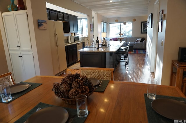 kitchen featuring appliances with stainless steel finishes, a center island, light hardwood / wood-style flooring, a breakfast bar area, and beam ceiling