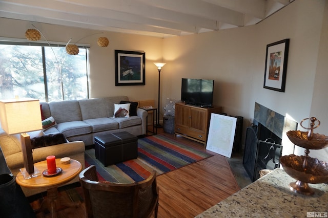 living room featuring a tile fireplace, beam ceiling, and dark hardwood / wood-style flooring