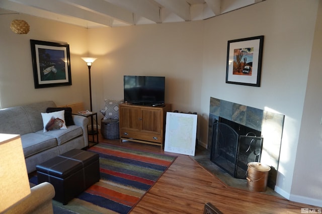 living room with a tile fireplace, dark hardwood / wood-style floors, and beam ceiling