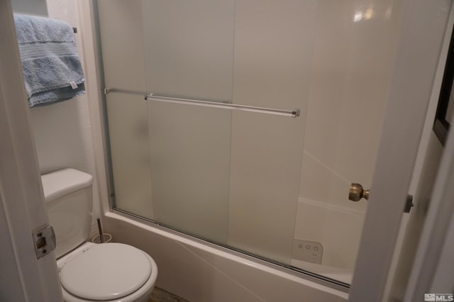 bathroom featuring toilet and combined bath / shower with glass door