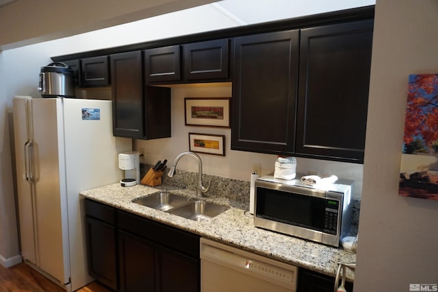 kitchen with white appliances, light stone countertops, sink, and hardwood / wood-style flooring