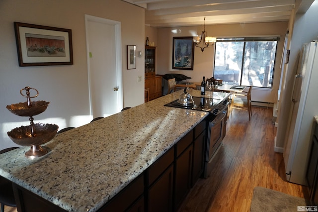 kitchen featuring a center island, hardwood / wood-style floors, hanging light fixtures, light stone countertops, and electric stove