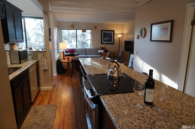 kitchen featuring stainless steel appliances, dark hardwood / wood-style flooring, light stone counters, and beam ceiling