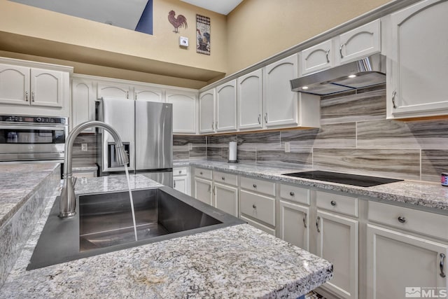 kitchen with appliances with stainless steel finishes, white cabinetry, sink, and tasteful backsplash