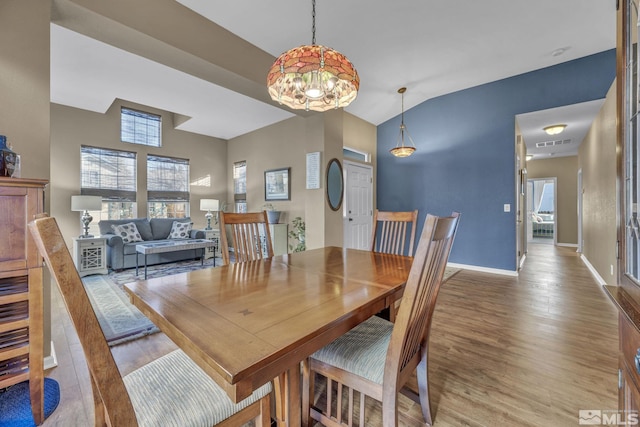 dining space featuring lofted ceiling, a notable chandelier, and hardwood / wood-style floors