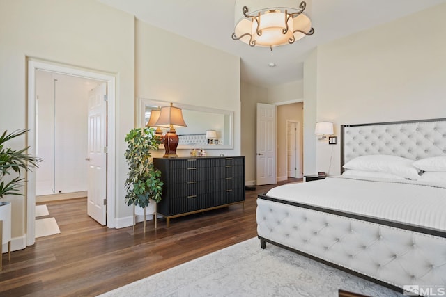 bedroom with ensuite bathroom and dark wood-type flooring