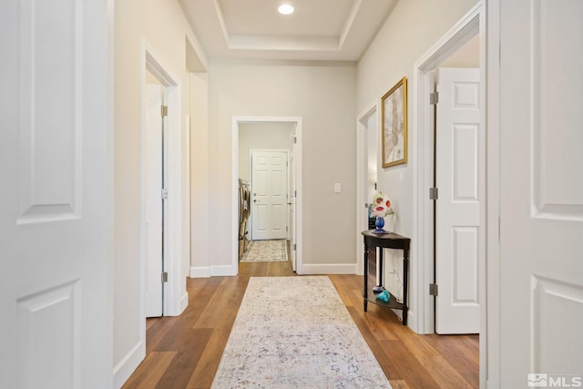 hallway with light hardwood / wood-style floors and a tray ceiling