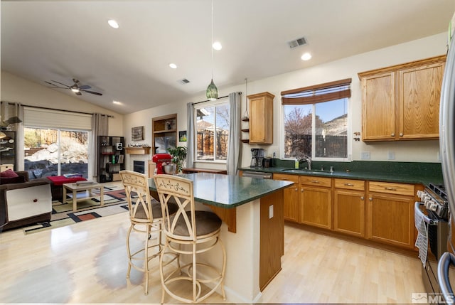 kitchen with vaulted ceiling, a healthy amount of sunlight, a center island, light hardwood / wood-style floors, and sink