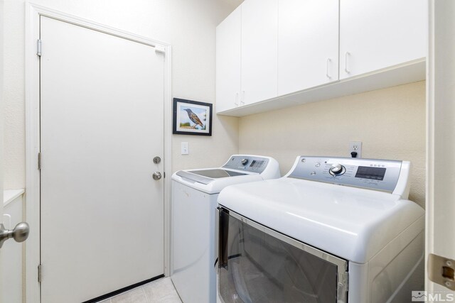 clothes washing area with light tile patterned floors, separate washer and dryer, and cabinets