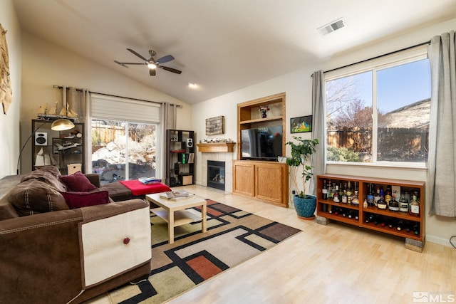 living room with light wood-type flooring, vaulted ceiling, and a wealth of natural light