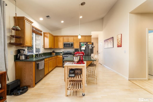 kitchen with hanging light fixtures, light hardwood / wood-style floors, a kitchen island, appliances with stainless steel finishes, and sink