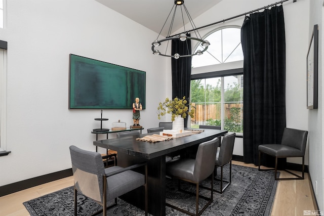 dining area with a notable chandelier, vaulted ceiling, and wood-type flooring