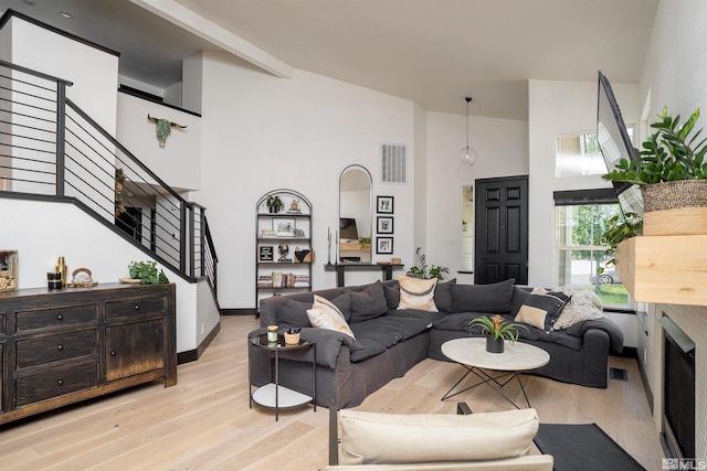 living room featuring high vaulted ceiling and light hardwood / wood-style floors