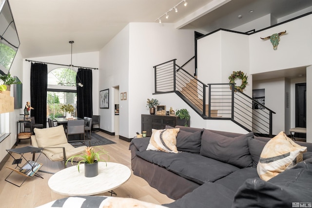 living room with light hardwood / wood-style floors, track lighting, and vaulted ceiling