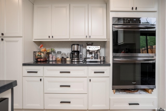 kitchen featuring double oven, white cabinets, and backsplash