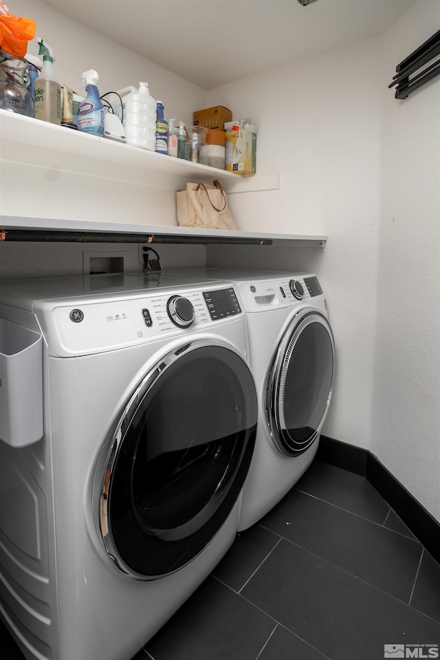 washroom featuring independent washer and dryer and dark tile patterned floors