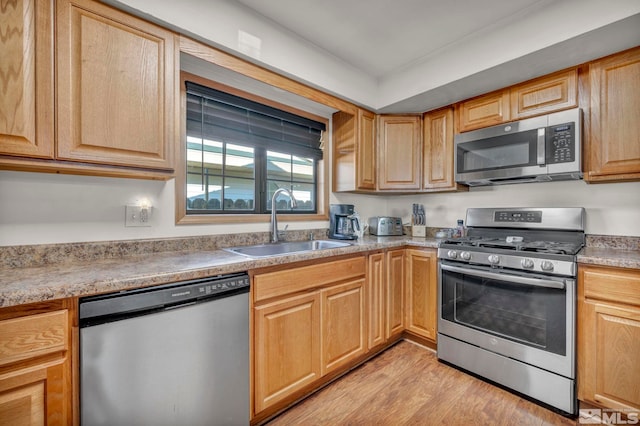 kitchen with stainless steel appliances, sink, and light hardwood / wood-style floors