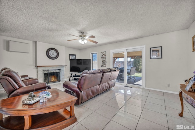 living room featuring a brick fireplace, a textured ceiling, ceiling fan, and light tile patterned floors