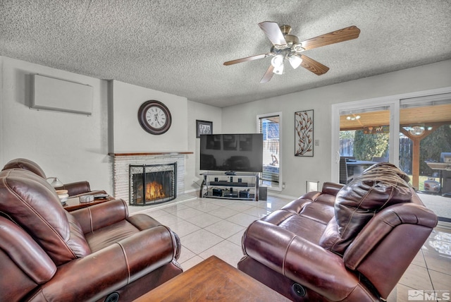 living room with ceiling fan, a textured ceiling, a fireplace, and light tile patterned floors