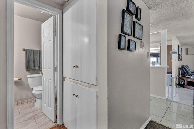 corridor with a textured ceiling and light tile patterned floors