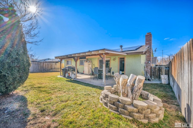 back of house with a lawn, a patio, and solar panels