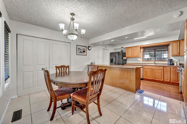 tiled dining room with sink, a textured ceiling, and a notable chandelier