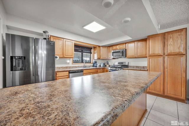 kitchen with stainless steel appliances, a raised ceiling, light tile patterned flooring, and sink