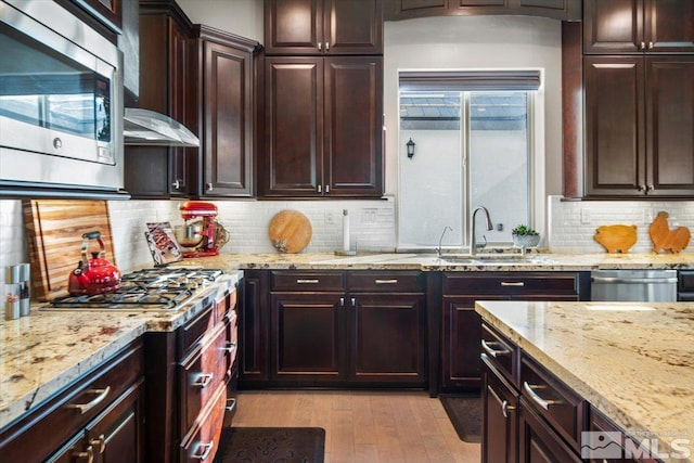 kitchen with sink, light hardwood / wood-style floors, backsplash, and appliances with stainless steel finishes