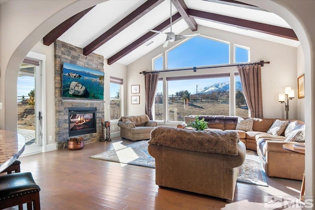 living room with hardwood / wood-style floors, ceiling fan, high vaulted ceiling, a fireplace, and beam ceiling