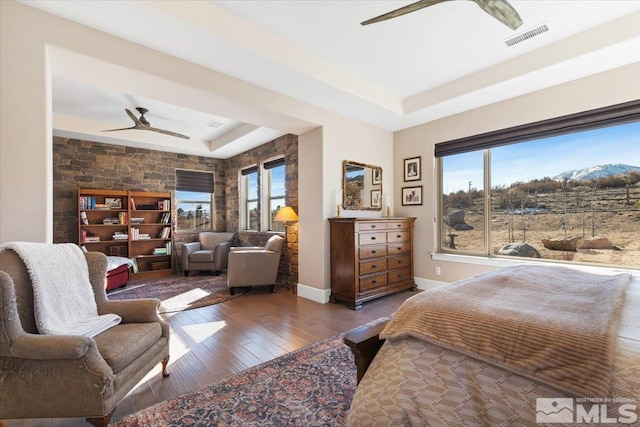 bedroom with ceiling fan, a raised ceiling, and dark hardwood / wood-style floors